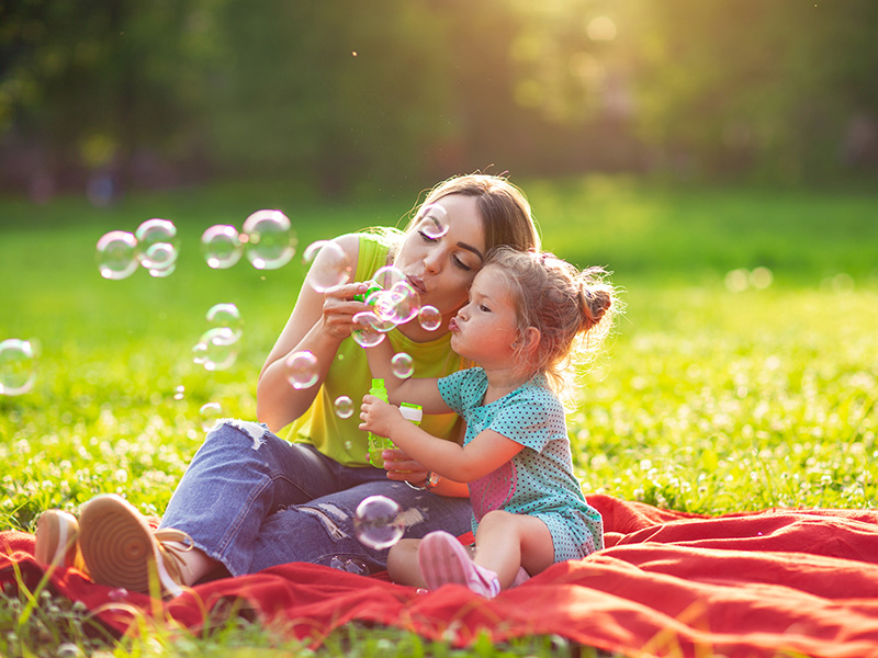 Mother and daughter blowing bubbles outside during springtime activities